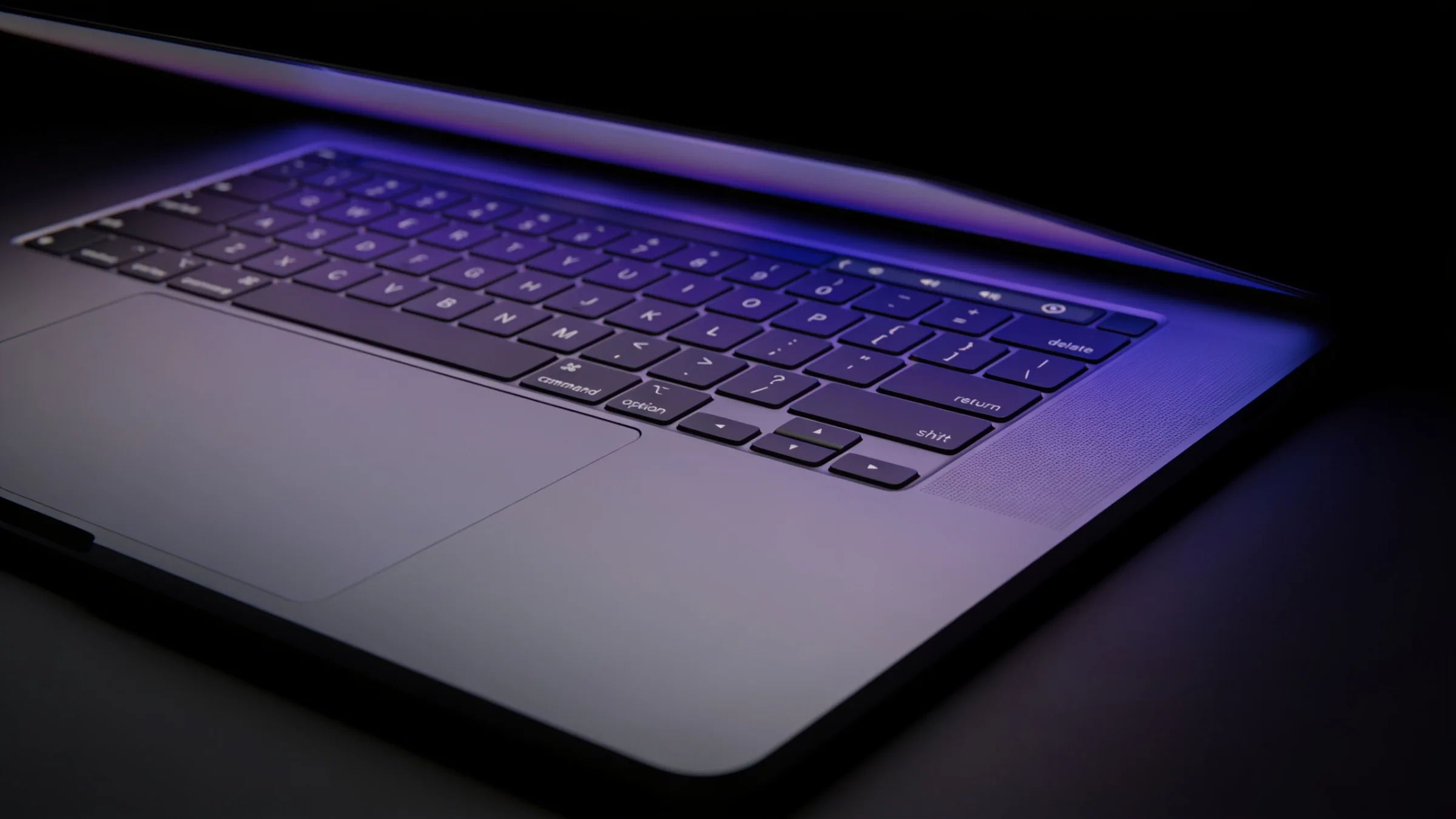 Close-up of a laptop keyboard edge lit by a soft indigo glow in a dark room
