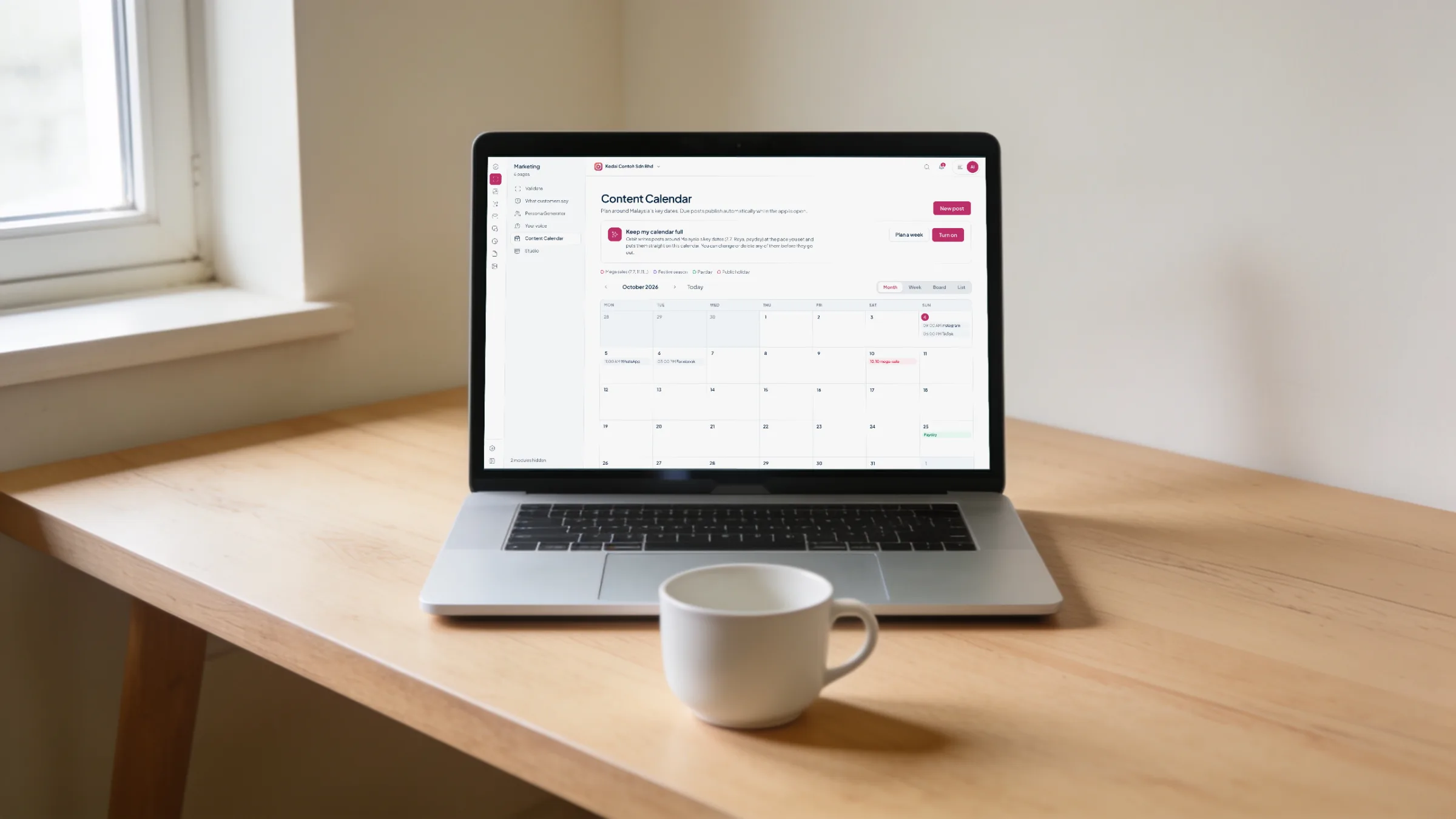 A laptop on an oak desk in morning light showing the Orbit Marketing content calendar for October 2026 with Malaysian key dates
