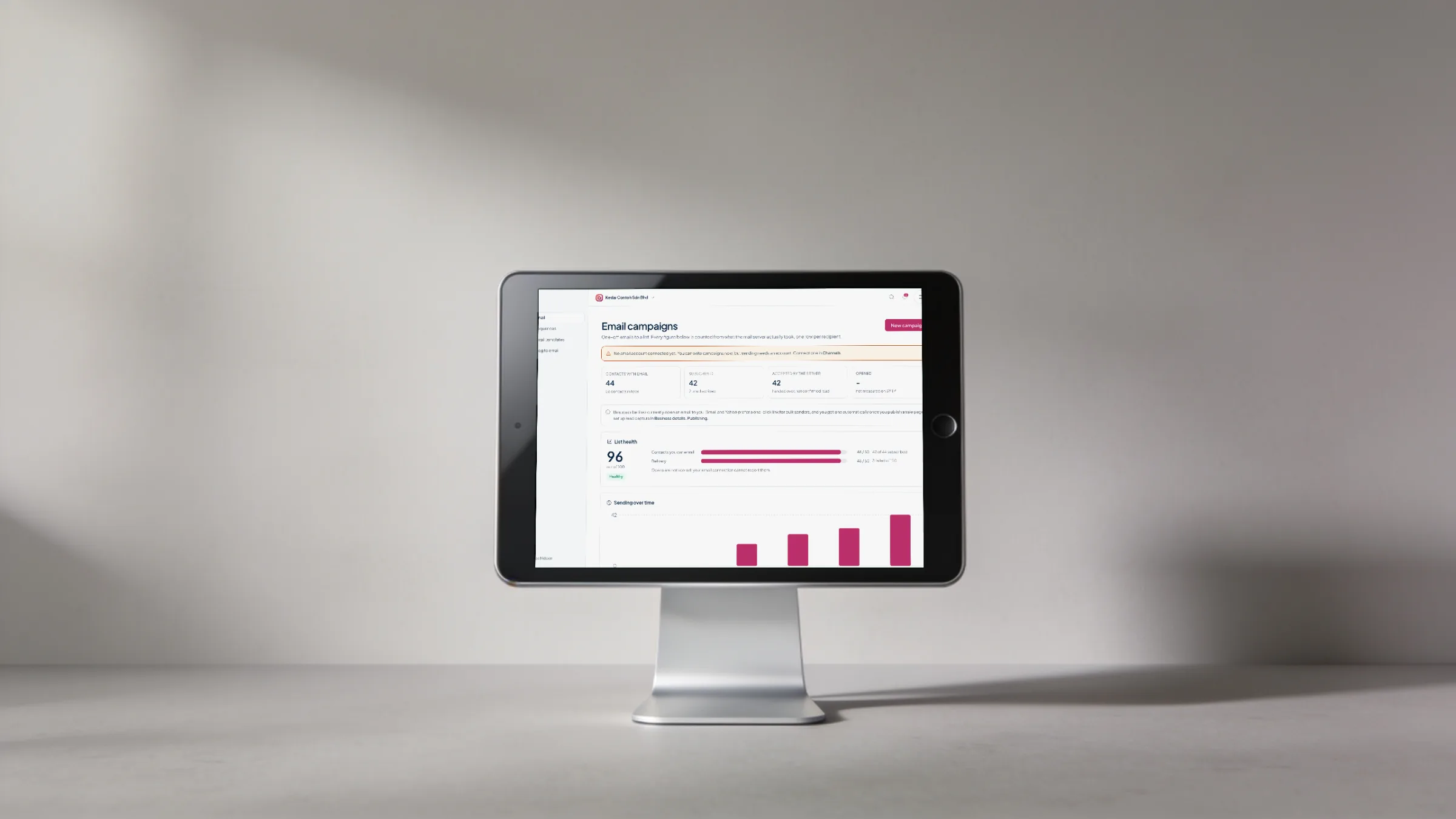 A tablet on a stand showing Orbit Marketing email campaigns: 44 contacts with email, list health 96 and sends over time